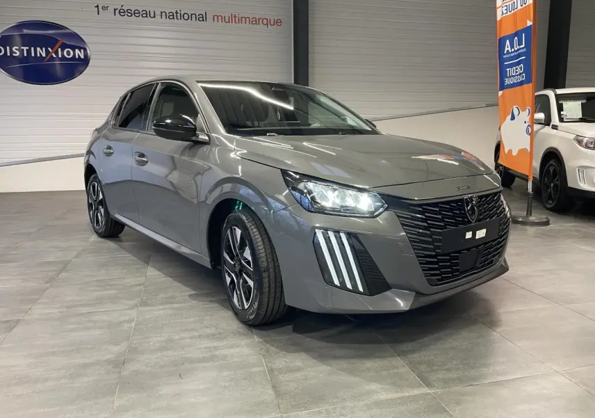 Peugeot 208 gris selenium en 3/4 avant droit avec calandre noire et feux LED distinctifs allumés.