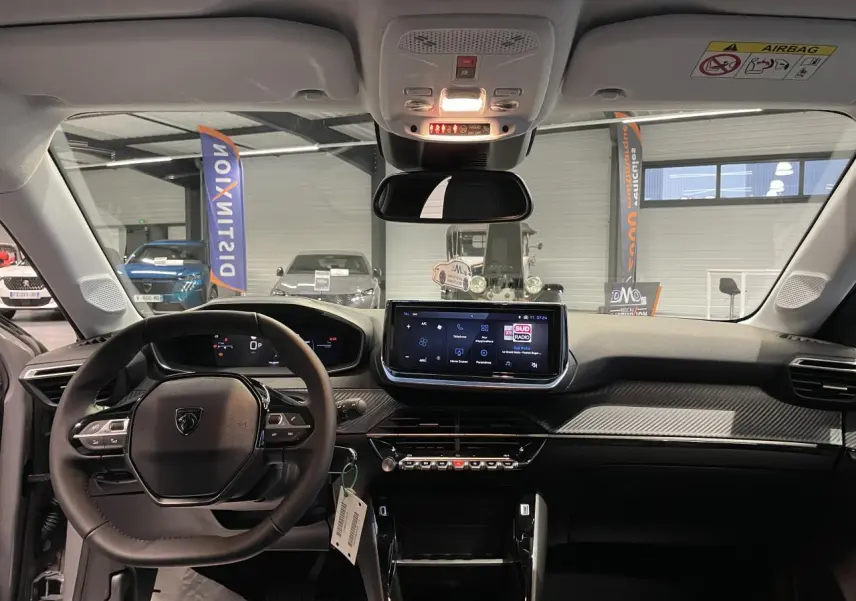 Vue intérieure avant du Peugeot 208 gris Selenium, tableau de bord avec écran tactile et volant compact cuir noir.
