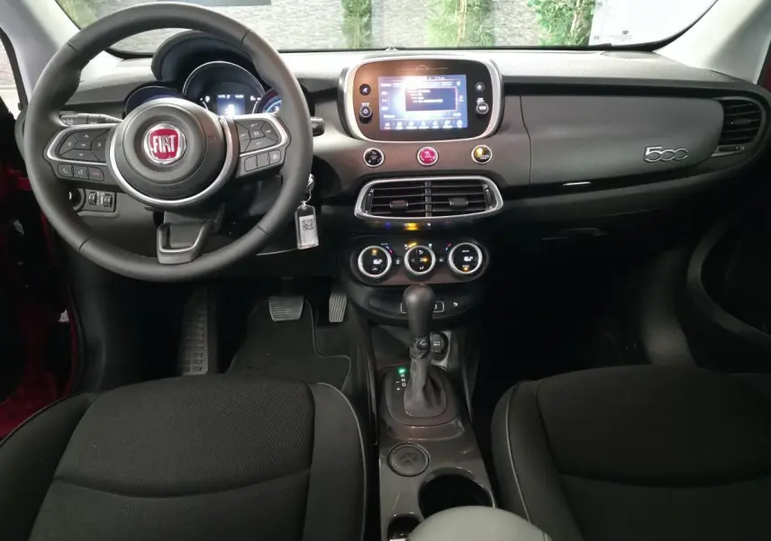 Vue intérieure frontale du tableau de bord du Fiat 500X 2024 avec volant multifonction et écran tactile central.