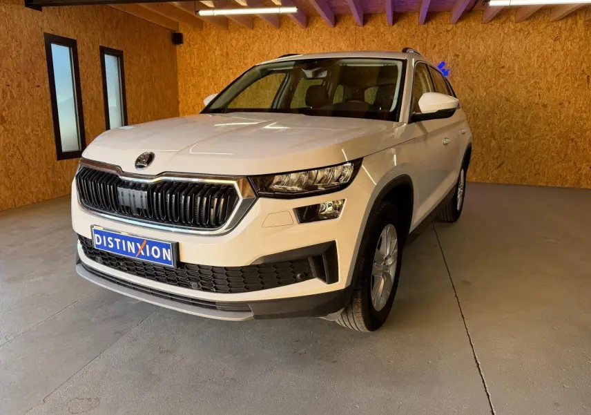 Vue 3/4 avant droite d'un Skoda Kodiaq blanc 2023 avec calandre noire et jantes alliage visibles.