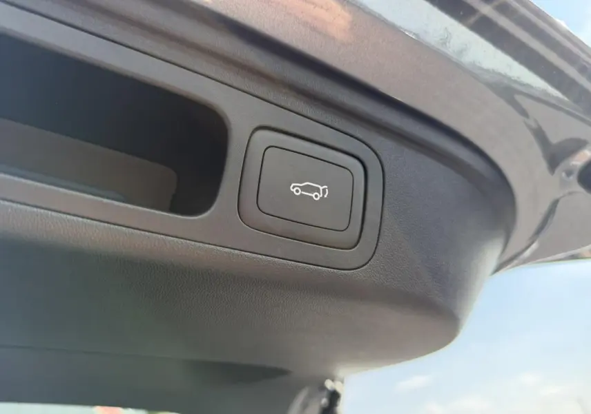 Bouton d'ouverture électrique du hayon sur la partie intérieure du coffre d'un MG Motor EHS gris.