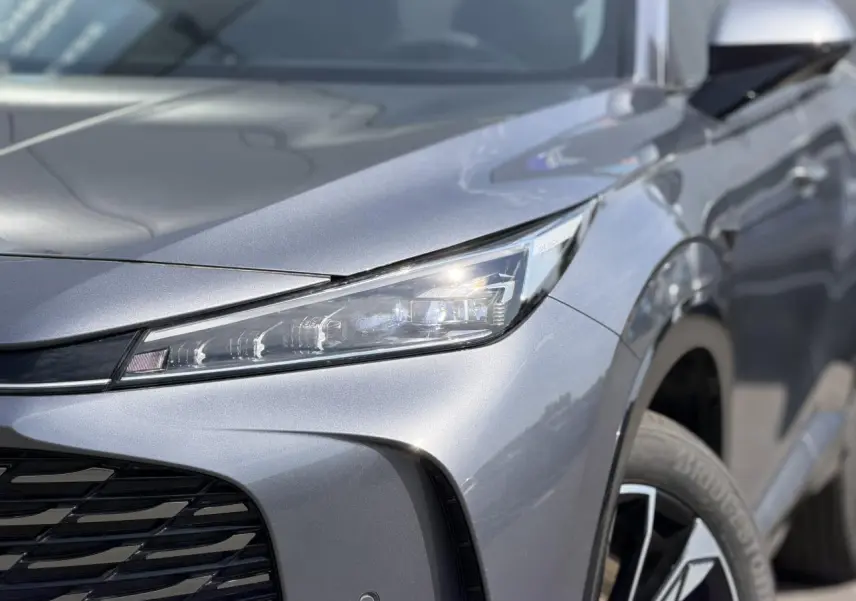 Gros plan sur l'avant droit gris métallisé du MG MOTOR EHS 1.5 Hybrid+ 224 Luxury avec phare LED et jante alliage 19 pouces.