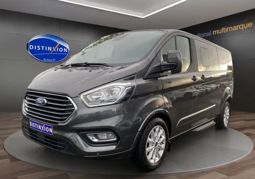 Ford Tourneo Custom gris magnetic vu en 3/4 avant droit, avec jantes alliage et porte latérale coulissante.