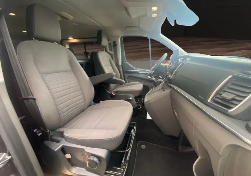 Vue intérieure côté conducteur du Ford Tourneo Custom 2020, montrant les sièges gris et le tableau de bord moderne.