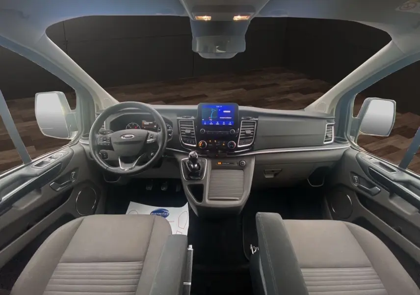 Vue intérieure frontale du Ford Tourneo Custom 2020 avec tableau de bord moderne et sièges noirs en tissu.