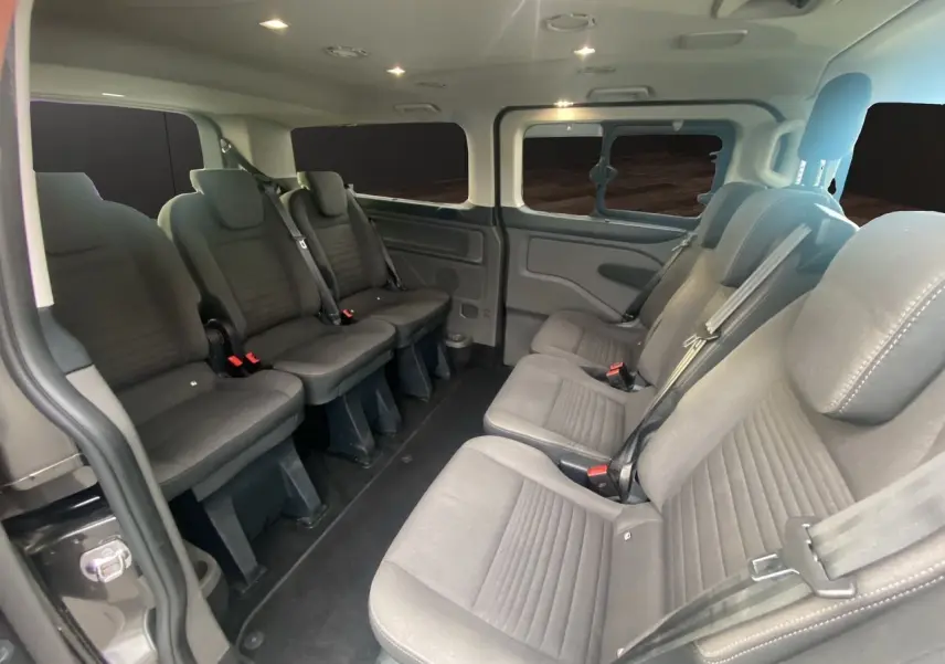 Vue intérieure du Ford Tourneo Custom 2020 montrant les sièges en tissu gris et l'aménagement spacieux pour 8 passagers.