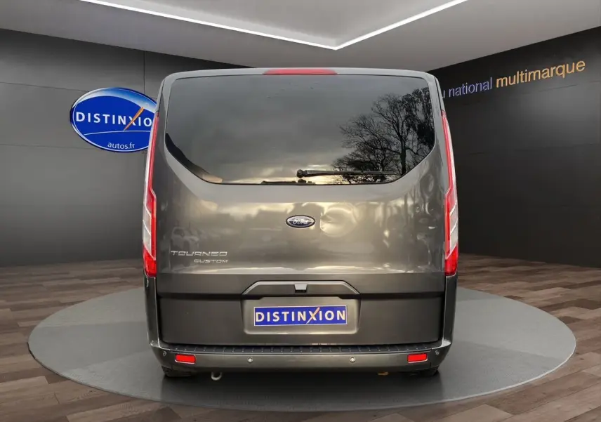 Vue arrière d'un Ford Tourneo Custom gris magnetic avec vitre teintée et feux verticaux rouges.