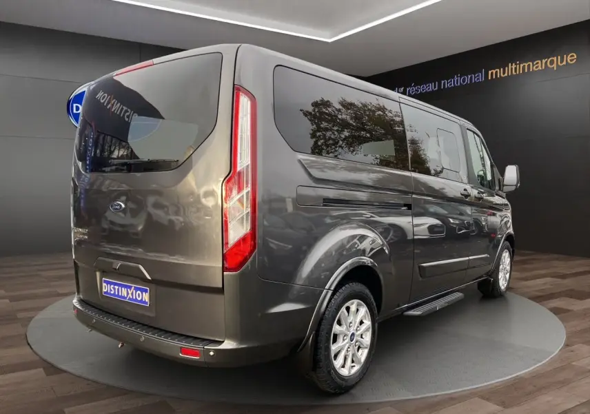 Vue 3/4 arrière droite d'un Ford Tourneo Custom gris magnetic avec vitres teintées et jantes alliage.