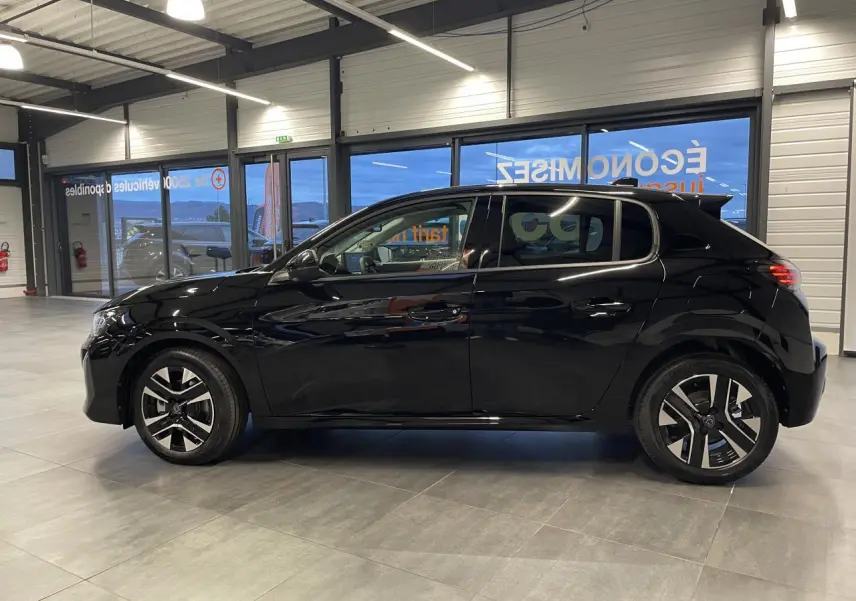 Profil droit d'une Peugeot 208 noire métallisée 2025 en showroom, avec jantes alliage bi-tons et vitres teintées.