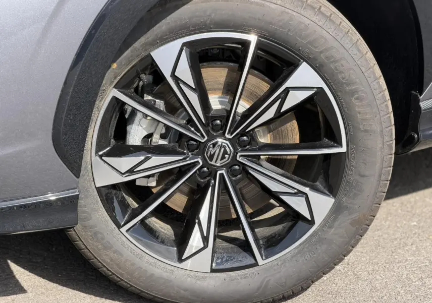 Gros plan sur la jante alliage 19'' noire et argentée du MG MOTOR EHS gris 2026, avec logo MG au centre.