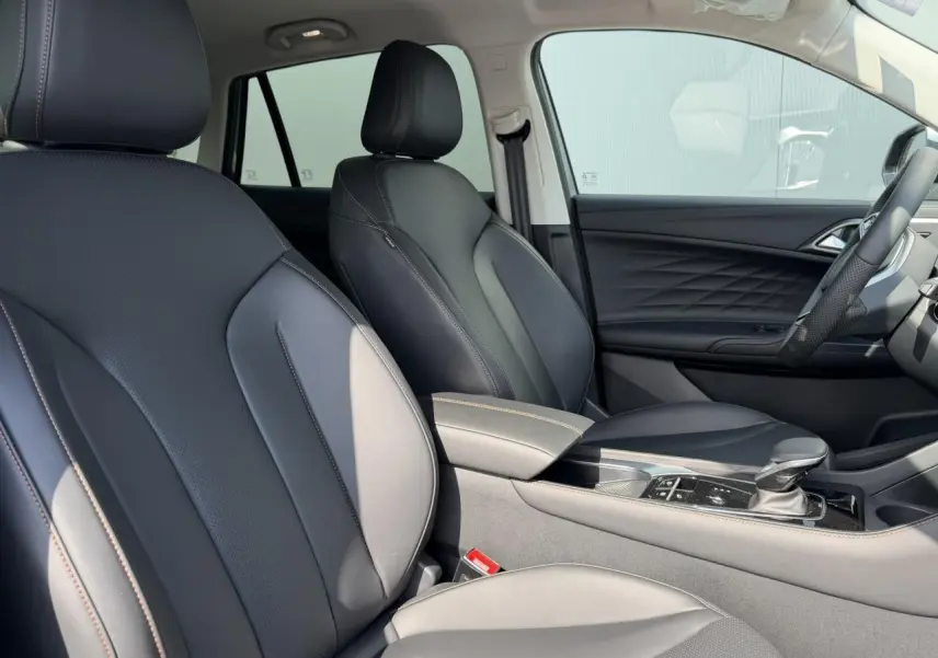 Vue intérieure côté droit du MG MOTOR EHS 1.5 Hybrid+ 224 Luxury 2026 avec sellerie simili cuir noir et accoudoir central.