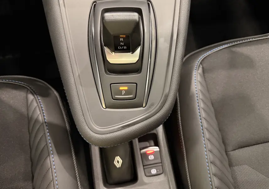 Vue rapprochée de la console centrale du Renault Symbioz gris Rafale, avec levier de vitesse automatique et surpiqûres bleues.