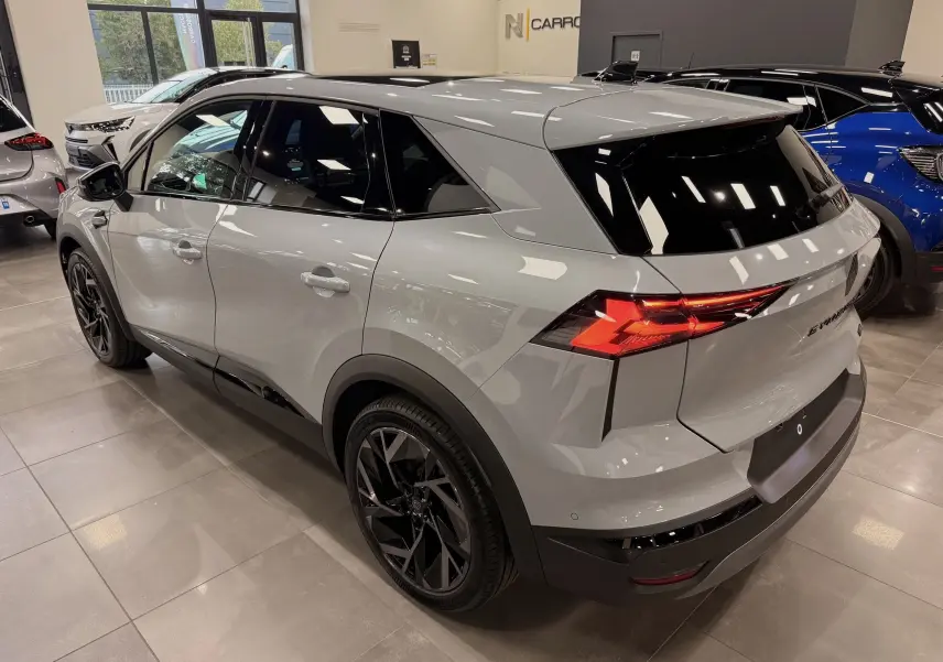Renault Symbioz E-Tech gris Rafale, vue 3/4 arrière droit, feux arrière LED et jantes noires biton visibles.