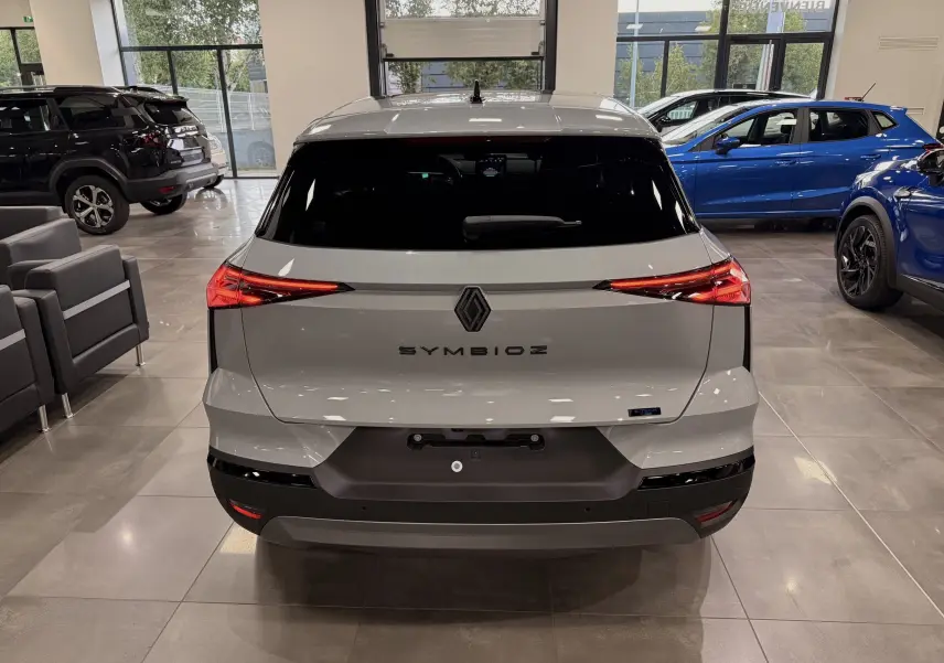 Vue arrière d’un Renault SYMBIOZ gris Rafale en showroom, avec feux arrière LED allumés et logo central visible.