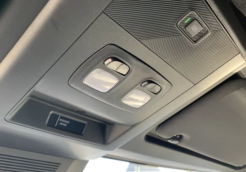 Plafonnier intérieur avec commandes d'éclairage et bouton SOS du Renault Master blanc, vue en contre-plongée côté conducteur.
