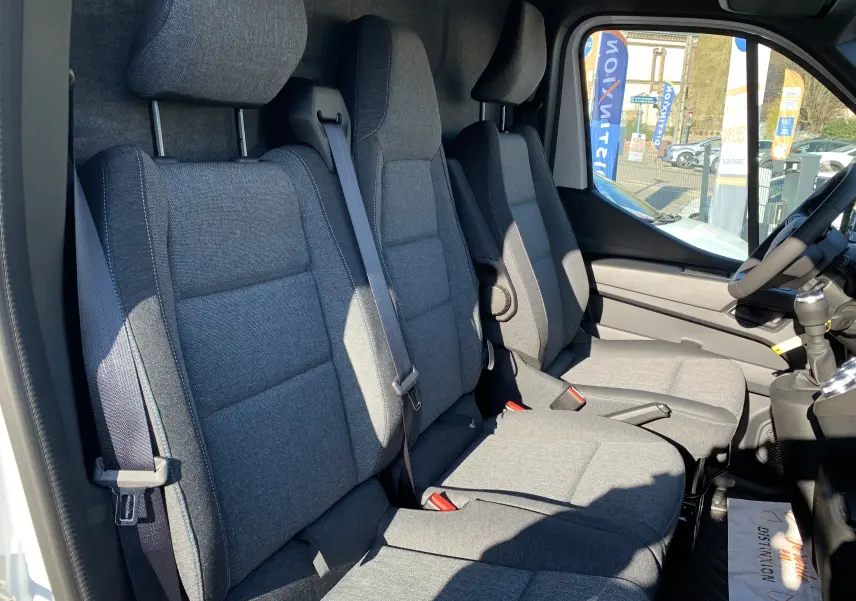 Intérieur du Renault Master 2025 vu côté conducteur, sièges tissu gris avec ceintures de sécurité visibles.