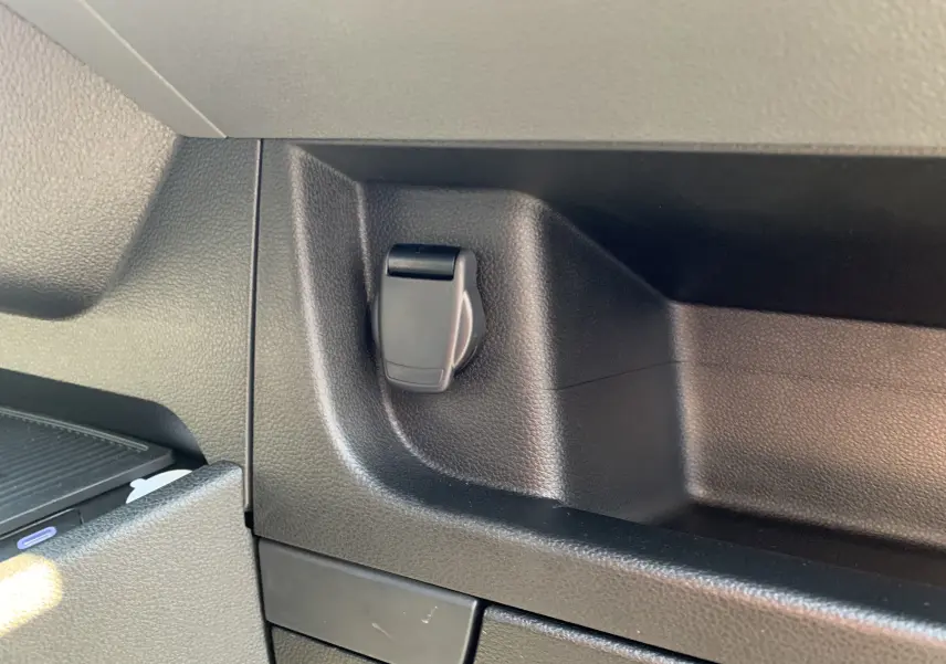 Prise 12V noire intégrée dans la console intérieure du Renault Master blanc mine, vue rapprochée côté droit.