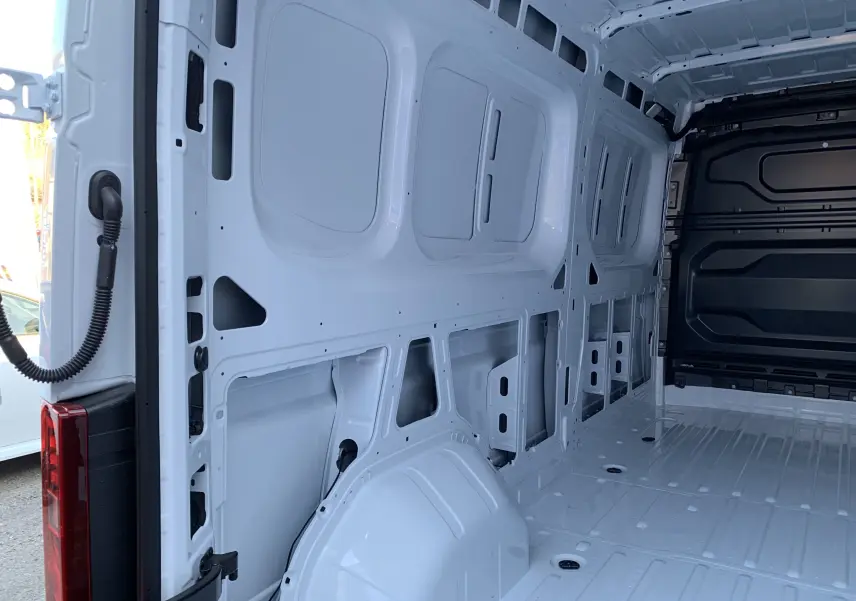 Vue intérieure arrière du fourgon Renault Master blanc mine, montrant la structure métallique nue et l'espace de chargement vide.