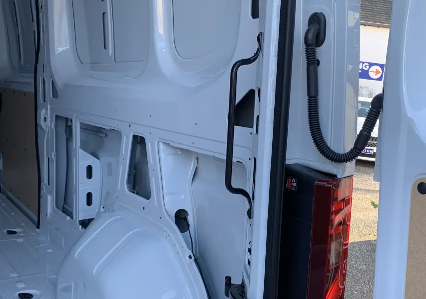 Vue intérieure arrière droite du Renault Master blanc mine, montrant la structure métallique et la porte ouverte avec feu arrière visible.