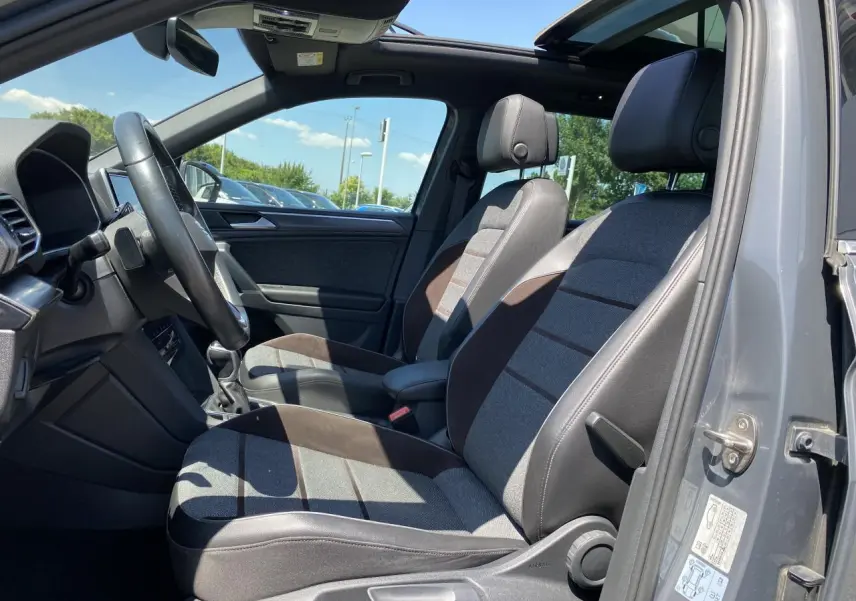 Intérieur du SEAT Tarraco gris dauphin vu côté gauche, sièges tissu gris et Alcantara, toit ouvrant panoramique ouvert.