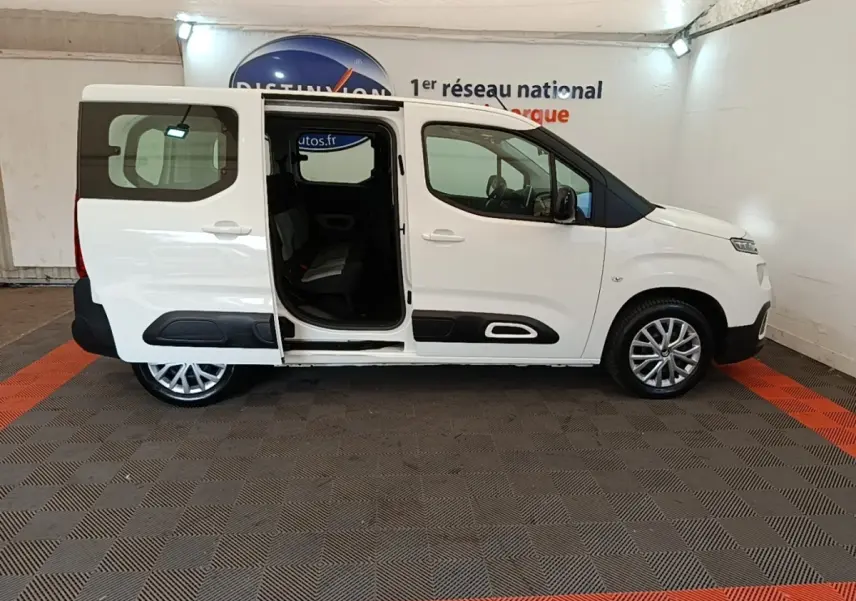 Profil droit d’un Citroën Berlingo blanc 2022 avec porte coulissante arrière ouverte en intérieur showroom.
