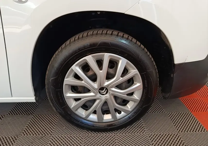 Gros plan sur la roue avant gauche blanche d’un Citroën Berlingo avec jante argentée au design moderne.