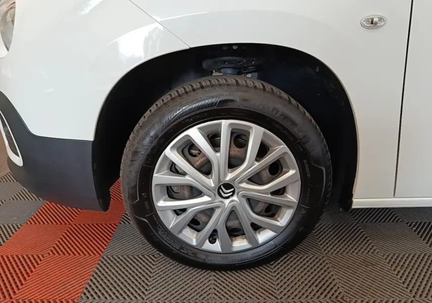 Gros plan sur la roue avant droite d’un Citroën Berlingo blanc avec jante en alliage et logo Citroën visible.