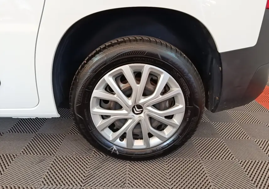 Gros plan sur la roue arrière droite d'un Citroën Berlingo blanc avec jante alliage et logo Citroën visible.