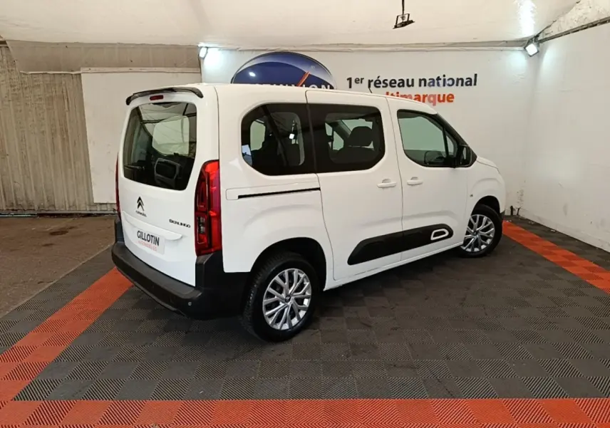 Vue 3/4 arrière droite d'un Citroën Berlingo blanc avec protections latérales noires et jantes alliage.
