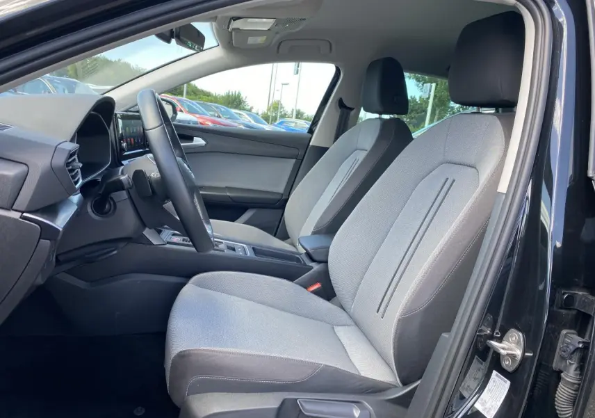 Intérieur côté conducteur d'une SEAT LEON 2024 noir Midnight, sièges tissu gris et tableau de bord moderne.