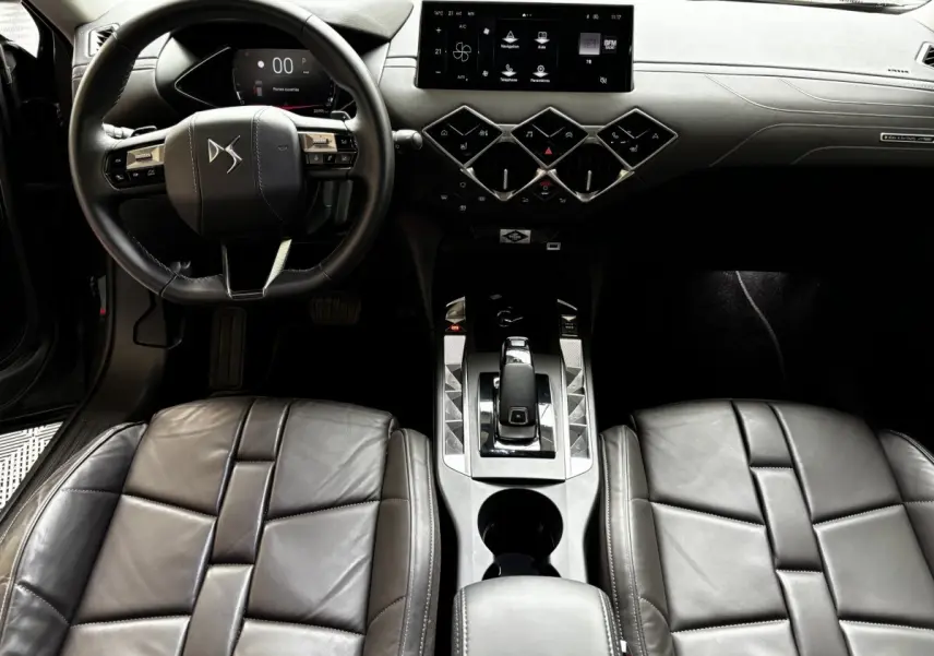 Vue intérieure avant du DS3 2024, tableau de bord et console centrale avec écran tactile 10,3 pouces et sièges cuir gris foncé.