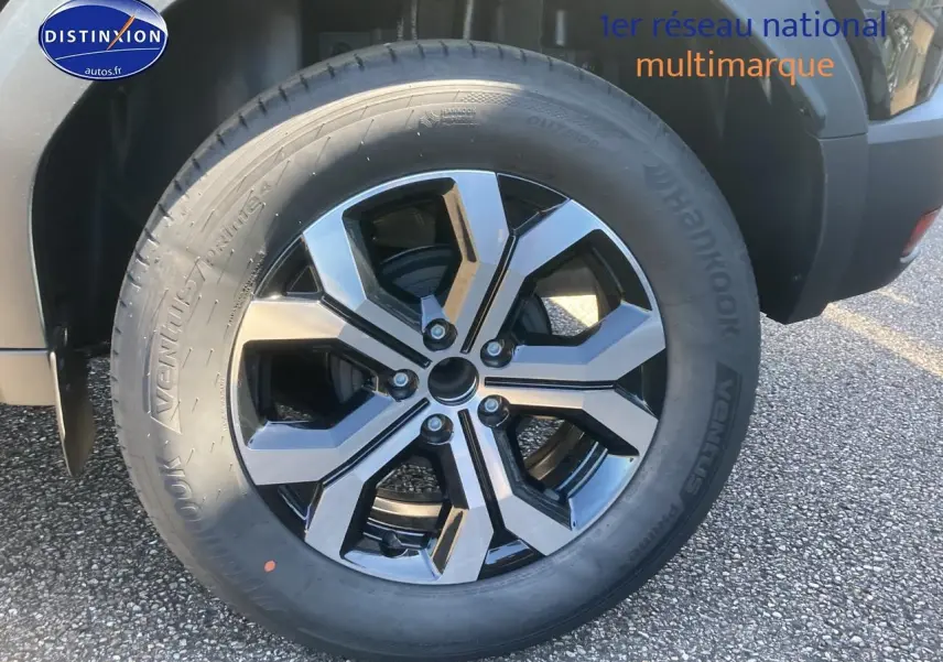 Gros plan sur la jante alu noire et argentée du côté arrière droit d’un Dacia Duster noir 2025.