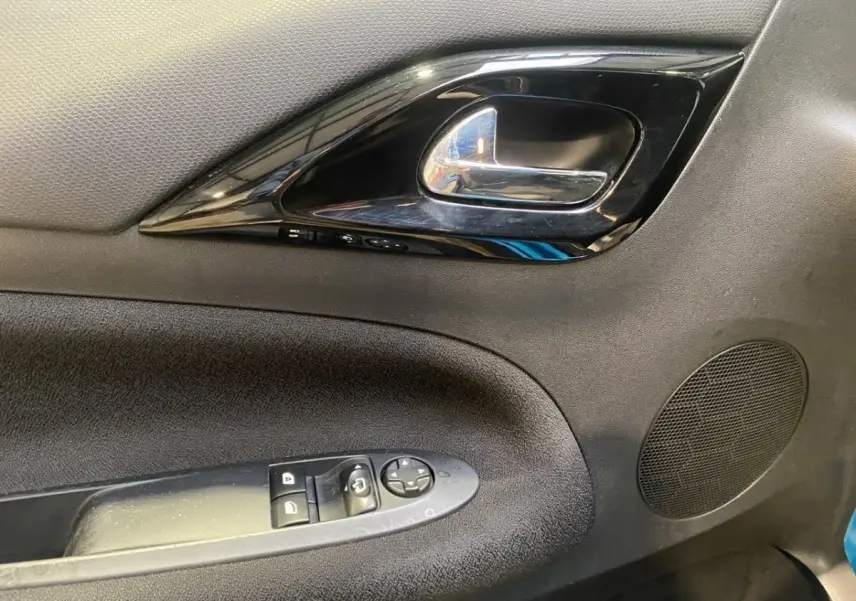 Gros plan sur la poignée intérieure et les commandes de fenêtre de la porte avant gauche d'une Citroën DS3 bleu 2011.