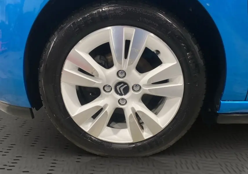 Gros plan sur la roue avant gauche d'une Citroën DS3 bleu, avec jante alliage argentée et logo Citroën central.