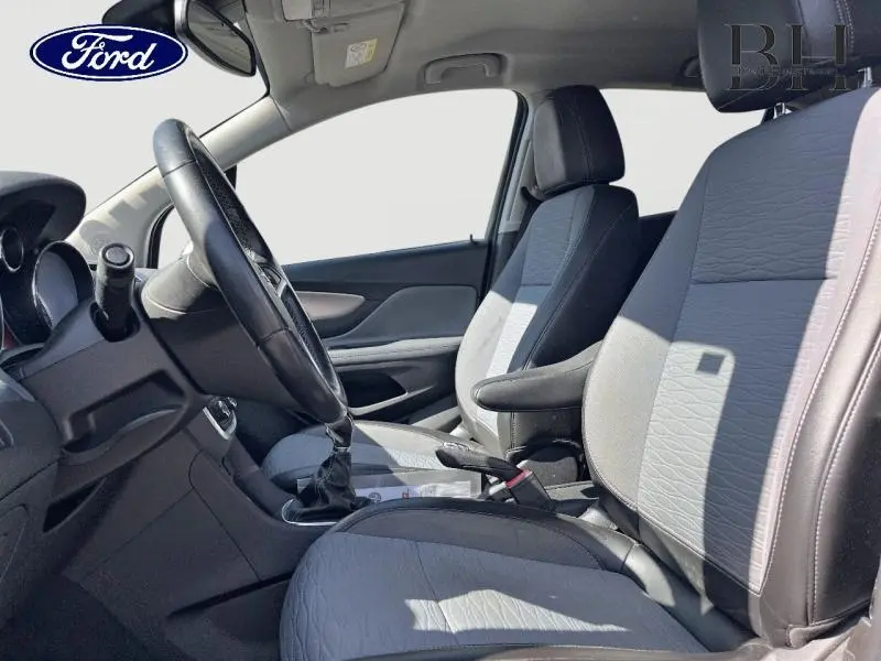 Vue intérieure côté conducteur d'une Opel Mokka gris minéral, montrant les sièges avant et le volant cuir multifonction.