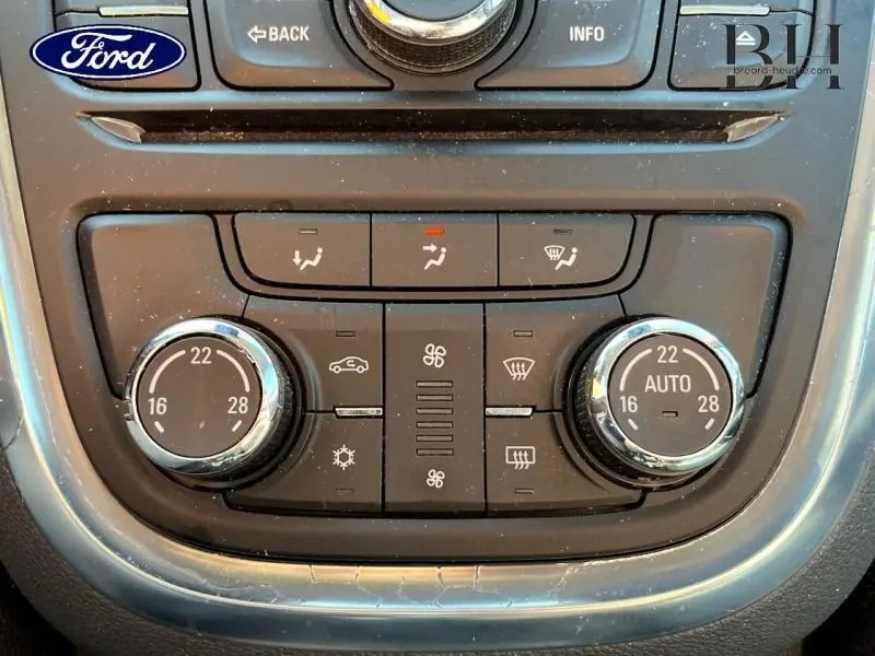 Panneau de commande de climatisation automatique noir avec boutons ronds chromés, vue en gros plan intérieur.