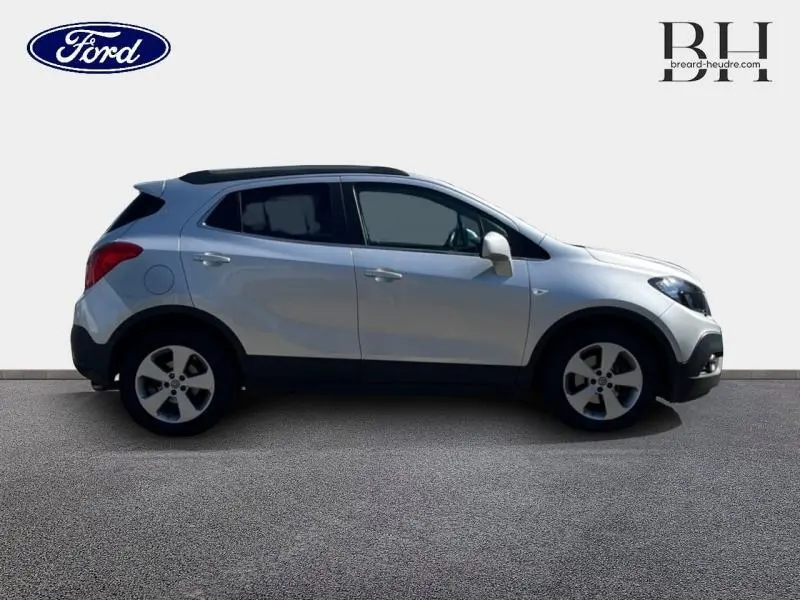 Profil droit d'un Opel Mokka gris minéral 2016 avec jantes alliage et toit noir contrastant.