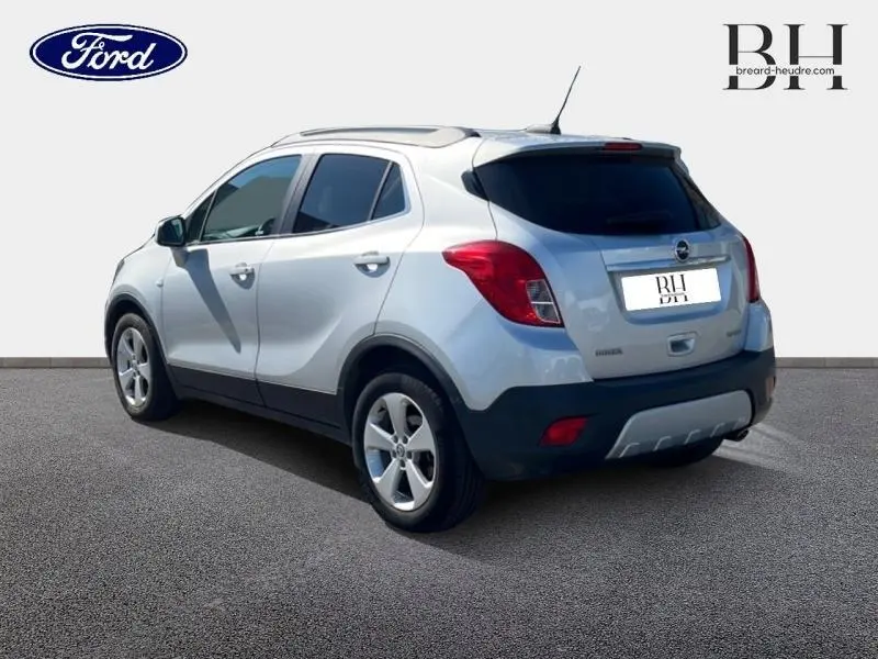 Vue 3/4 arrière droit d'un Opel Mokka gris minéral avec vitres teintées et jantes alliage.