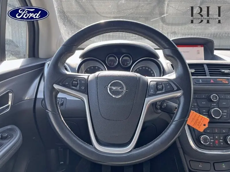 Vue intérieure centrée sur le volant cuir Opel avec tableau de bord et console centrale noire.