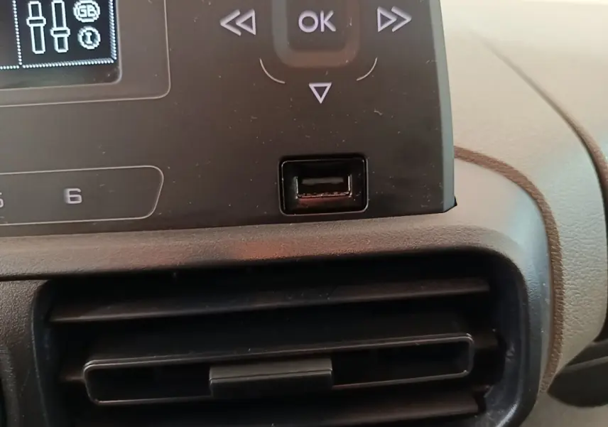 Gros plan sur la console centrale noire du Peugeot Rifter blanc, montrant les commandes et une prise USB.