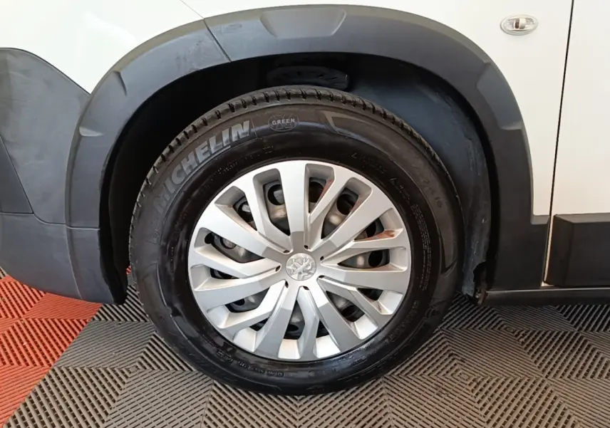 Gros plan sur la roue avant droite d’un Peugeot Rifter blanc, avec jante argentée et pneu Michelin.