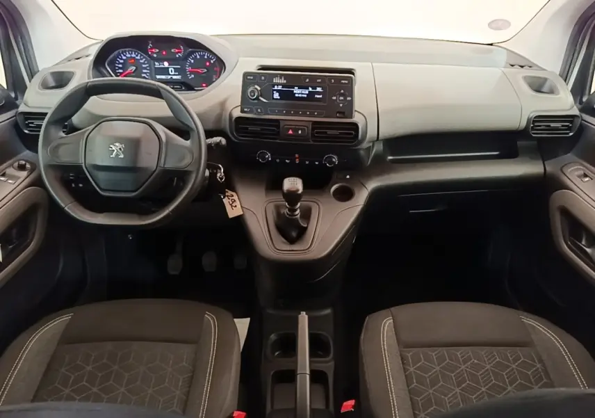 Vue intérieure avant du Peugeot Rifter blanc 2020, montrant le volant, tableau de bord et levier de vitesses manuel.