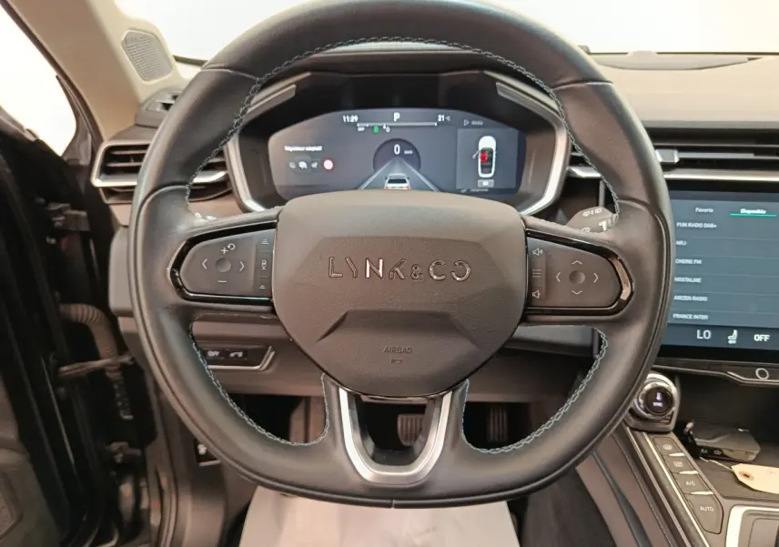 Vue intérieure centrée sur le volant cuir noir du Lynk & Co 01 avec tableau de bord digital et écran tactile.