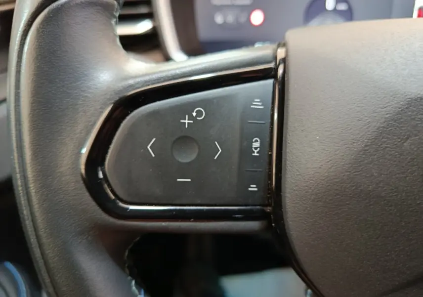 Gros plan sur les commandes noires du volant côté gauche du LINK & CO 01 hybride rechargeable 2022.