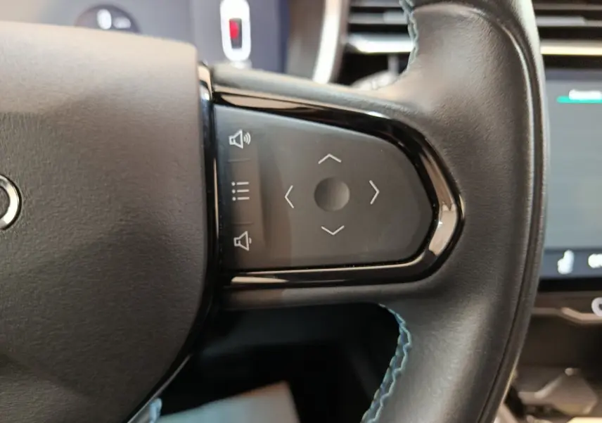 Gros plan sur les commandes tactiles noires du volant en cuir noir avec surpiqûres bleues du LINK & CO 01 hybride rechargeable.