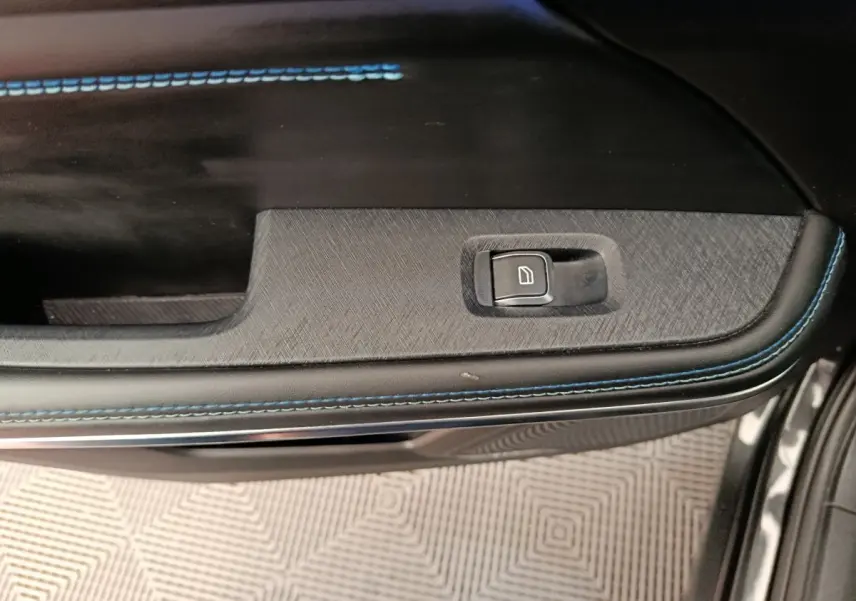 Détail de la commande de lève-vitre sur la porte intérieure noire avec surpiqûres bleues du LINK & CO 01 hybride rechargeable.