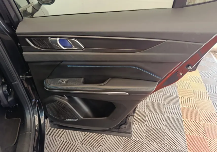 Vue intérieure côté gauche de la porte avant d’un Link & Co 01 bleu, avec éclairage d’ambiance bleu et finitions noires.