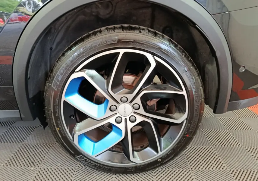 Gros plan sur la roue avant droite du SUV Link & Co 01 bleu, avec jante noire et inserts bleus distinctifs.