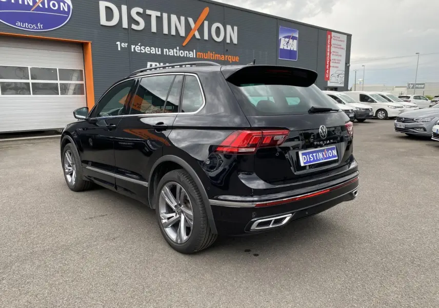 Volkswagen Tiguan noir intense métallisé vu en 3/4 arrière droit, avec jantes alliage et feux LED distinctifs.