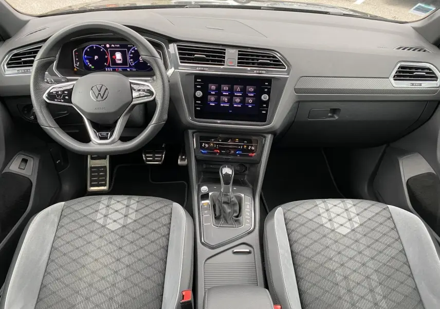 Intérieur du Volkswagen Tiguan 2023 vu de face, avec tableau de bord numérique et sellerie tissu gris à motifs géométriques.